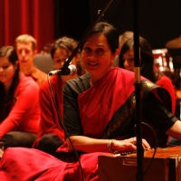Rita Sahai in red by an instrument
