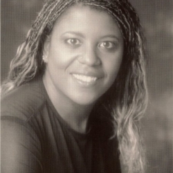Headshot for Dianthe Spencer, a Black woman with long hair smiling at the camera. The photograph is black-and-white.